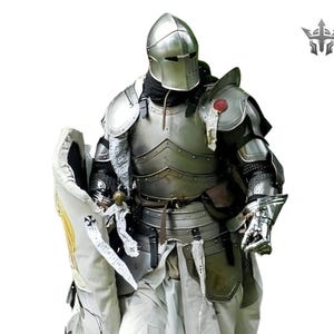May include: A full suit of polished steel armor, including a helmet, chest plate, and shoulder guards. The armor is worn over a white tunic and includes a shield with a cross design. A medieval knight's attire.