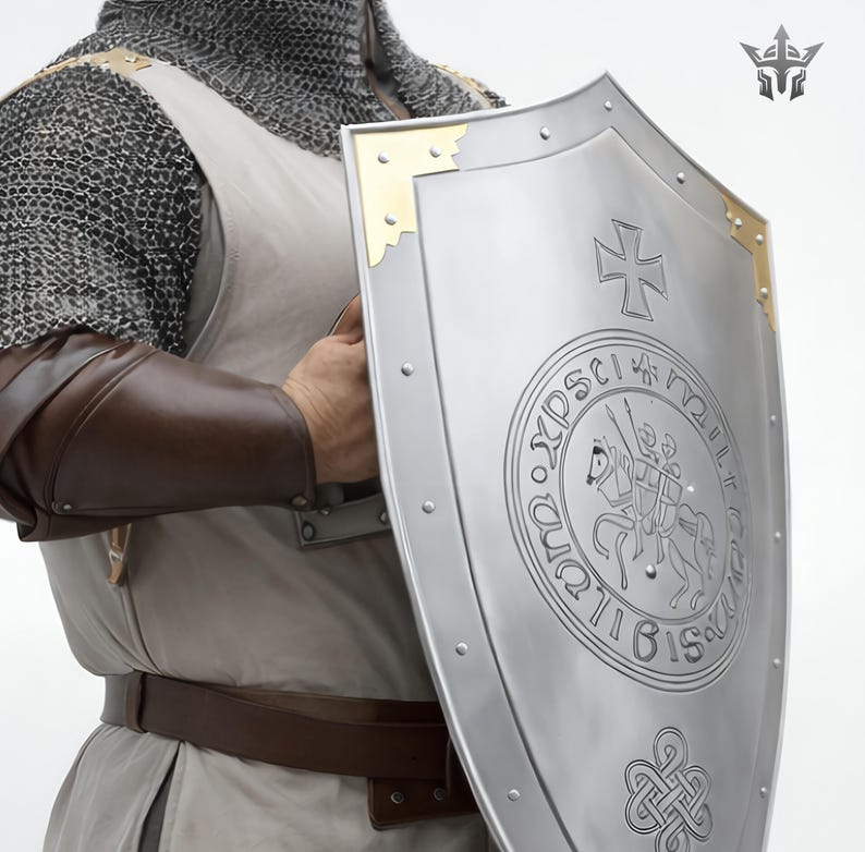 May include: A silver shield with a cross and a circular emblem featuring a knight on horseback. The shield has gold corner accents and is riveted around the edges. The shield is held by a person wearing chainmail and brown leather arm protection.