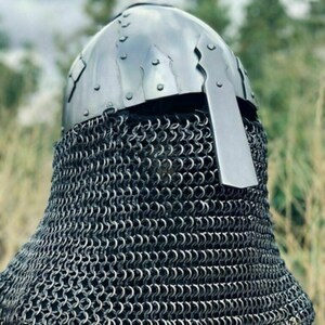 May include: A medieval-style helmet with a riveted, polished metal skullcap and a chainmail aventail. The helmet features a rectangular visor and is designed for protection. The chainmail extends to cover the neck and shoulders.
