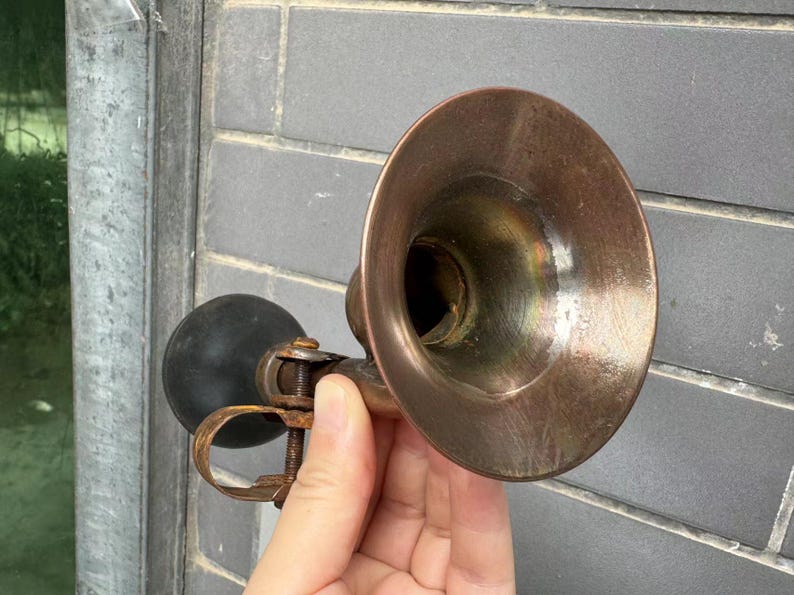 Puede incluir: Claxon de bicicleta vintage de lat&oacute;n con una pera de goma negra. El claxon tiene forma de campana acampanada y una abrazadera para sujetarlo a una bicicleta. El lat&oacute;n tiene una p&aacute;tina c&aacute;lida y envejecida. Un accesorio cl&aacute;sico para bicicletas vintage.