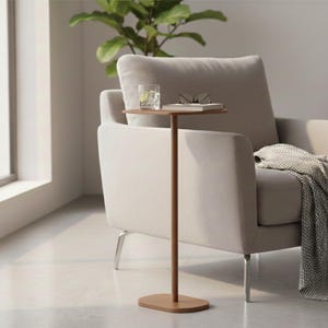 Op de afbeelding: Een moderne woonkamer met een lichtgrijze fauteuil en een grijze deken. Een kleine, bruine bijzettafel heeft een glas water en een bril. Een lamp en een houten kast staan op de achtergrond.