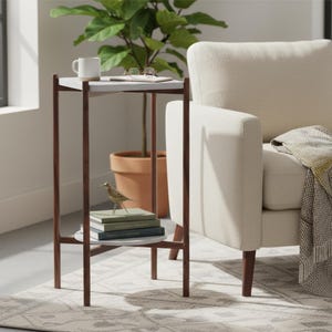 May include: A tall, square side table with a dark brown wooden frame and two white shelves. The top shelf holds a white mug and spectacles, while the bottom shelf holds a small metal bird figurine and a stack of two books.