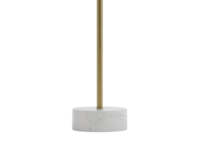 May include: A round marble table with a gold metal base. The table is white with gray veining and the base is a cylinder shape.