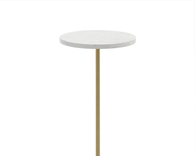 May include: A round marble table with a gold metal base. The table is white with gray veining and the base is a cylinder shape.