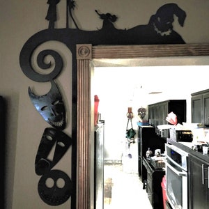 Peut inclure: Décoration murale en métal noir représentant des personnages du film L'Étrange Noël de monsieur Jack. La décoration est fixée au-dessus d'une porte et comprend Jack Skellington, Sally et Oogie Boogie.