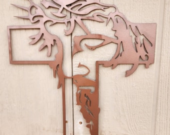 May include: A copper-colored metal cross with a detailed silhouette of Jesus's face and crown of thorns.