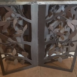 May include: A brown metal console table with a marble top. The table features a decorative design of leaves and branches.