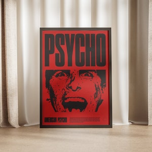 Könnte beinhalten: Ein schwarzer gerahmter Poster mit rotem Hintergrund und dem Wort "PSYCHO" in großen schwarzen Buchstaben. Der Poster zeigt ein Schwarzweißbild eines Mannes mit einem schreienden Ausdruck. Der Text "AMERICAN PSYCHO" befindet sich am unteren Rand des Posters.