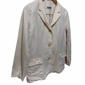Może przedstawiać: Kremowy blazer z lnu z metką Jil Sander. Blazer ma kołnierz szalowy, trzy guziki i dwie naszywane kieszenie.