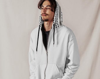 Puede incluir: Una sudadera blanca con cremallera y forro de capucha estampado, combinada con pantalones cortos vaqueros negros y zapatillas blancas. La sudadera tiene una cremallera negra y un corte holgado. Los pantalones cortos tienen un lavado oscuro.