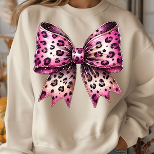 May include: A white sweatshirt with a large pink and brown leopard print bow on the front.
