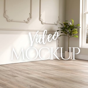 May include: A white canvas leaning against a wall with the words "Video MOCKUP" in white script. A potted plant sits to the right, and a window is visible in the background. The room has light-colored walls and a wood floor.