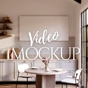 May include: A white framed video mockup in a modern kitchen with white cabinets, a wooden table, and two chairs. The kitchen has a large window with a view of green trees.