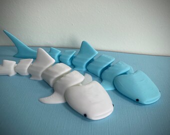 May include: Two segmented shark toys, one white and one light blue. The toys are made of plastic and have a realistic shark shape.