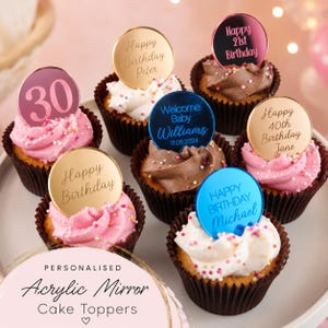 Puede incluir: Una colección de adornos redondos y personalizados para pasteles hechos de acrílico espejo en oro, oro rosa y azul, con textos grabados como Happy Birthday, 30 y Welcome Baby Williams, cada uno insertado en un cupcake con glaseado y chispas.