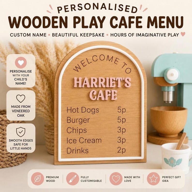 Puede incluir: Un letrero de men&uacute; de cafeter&iacute;a de juguete en madera con forma de arco que presenta el texto WELCOME TO HARRIET'S CAFE en letras rosas en relieve. La tabla enumera alimentos como Hot Dogs, Burger, Chips, Ice Cream y Drinks con sus precios.