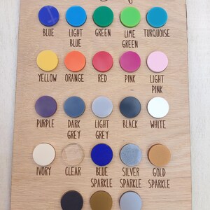Puede incluir: Una tabla rectangular de madera titulada Colour Samples que presenta veintitr&eacute;s muestras circulares de acr&iacute;lico en varios colores y acabados, incluyendo azul, verde, amarillo, naranja, rojo, rosa, morado, gris, negro, blanco, marfil, transparente y texturas brillantes o met&aacute;licas.