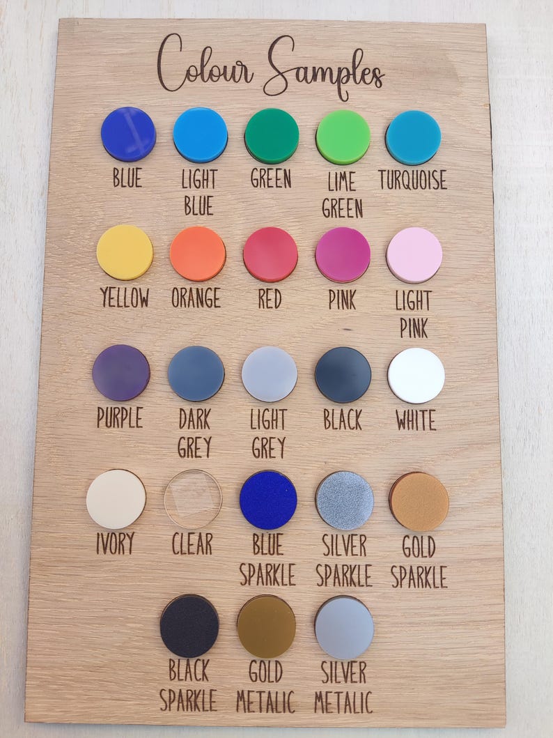 Puede incluir: Una tabla rectangular de madera titulada Colour Samples que presenta veintitr&eacute;s muestras circulares de acr&iacute;lico en varios colores y acabados, incluyendo azul, verde, amarillo, naranja, rojo, rosa, morado, gris, negro, blanco, marfil, transparente y texturas brillantes o met&aacute;licas.