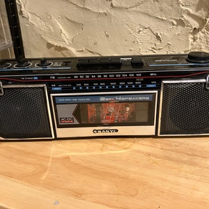 May include: A black and silver cassette player with a digital display and the text "2WAY 4 SPEAKERS" and "SANYO".