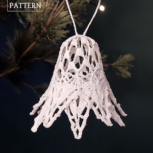 May include: White crocheted bell ornament hanging from a Christmas tree branch. The ornament has a delicate, lacy design and is perfect for adding a touch of vintage charm to your holiday decor.