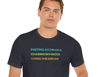 Könnte beinhalten: Ein dunkelblaues T-Shirt mit dem Text "POSTING ACCRUALS. CHASING INVOICES. LIVING THE DREAM." in einem Regenbogenfarbton.