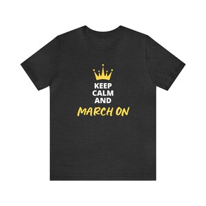 May include: A dark heather grey t-shirt with a gold crown and the text "Keep Calm and March On".
