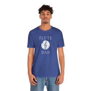May include: A blue t-shirt with a white distressed circle containing a treble clef and the text "FLUTE DAD".