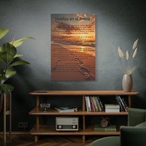 May include: A canvas print displays a sunset beach scene with footprints in the sand. The Spanish text "Huellas en la Arena" is at the top, with a poem below. The print is displayed on a dark wall above a wooden shelf with books and a vintage radio.