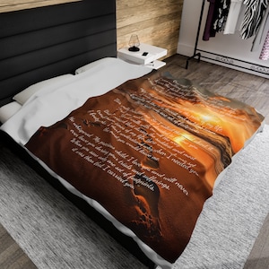 May include: A soft, white throw blanket with a sunset and beach scene. The blanket features a quote about the paths of life and the footprints of someone who walked with the author. The quote reads: "One night I prayed and asked the Lord to show me the paths of my life. He whispered, 'My precious child, I love you and will never leave you during your trials and sufferings. When you saw only one set of footprints, it was then that I carried you.'"