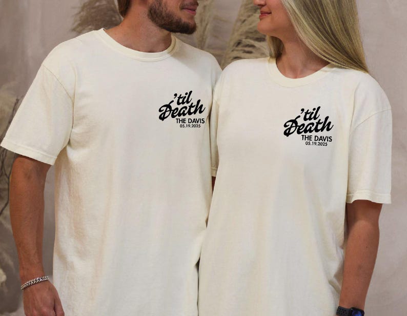 May include: Two cream-colored t-shirts with the phrase "'til Death" in a script font, along with "THE DAVIS 05.19.2025" printed in black. The shirts are worn by a couple, suggesting a matching set for a wedding or anniversary.