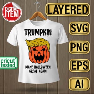 May include: White t-shirt featuring a pumpkin design with a face and a blonde hairstyle, with the word "TRUMPKIN" above it. The phrase "MAKE HALLOWEEN GREAT AGAIN" is below the pumpkin.