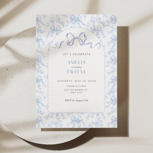 May include: A light blue and white invitation card with a bow and floral design. The text reads "LET'S CELEBRATE AMELIA is turning TWELVE." The invitation is for a party on Saturday, June 14, 2030, at 3:00 PM. RSVP by August 5th.