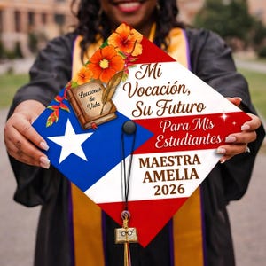 May include: A graduation cap featuring the Puerto Rican flag design, adorned with floral accents and text. The cap includes the words "Mi Vocación, Su Futuro Para Mis Estudiantes" and "Maestra Amelia 2026."