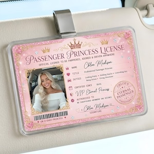 Peut inclure: Un permis rose de « Princesse Passagère » avec une photo d'une femme souriante. Le permis, tenu par un clip argenté, contient du texte tel que « Licence Officielle pour être choyée, adorée et conduite n'importe où » et « VIP Princesse Éternelle ».
