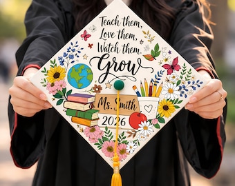 May include: A decorated graduation cap with the words "Teach them, Love them, Watch them, Grow." The cap features colorful floral and school-themed illustrations, including a globe, books, pencils, and an apple. The name "Ms. Smith" and the year "2026" are also displayed.