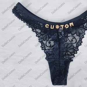 May include: Black lace underwear with a gold "CUSTOM" embellishment.