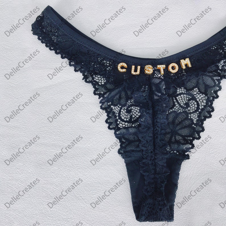 May include: Black lace underwear with a gold "CUSTOM" embellishment.