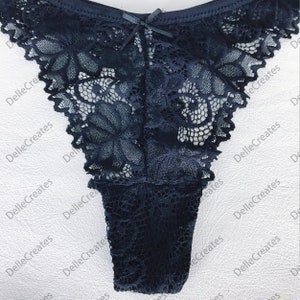 May include: Black lace underwear with a bow detail. The lace has a floral pattern.