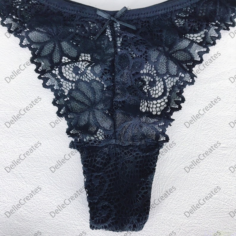 May include: Black lace underwear with a bow detail. The lace has a floral pattern.