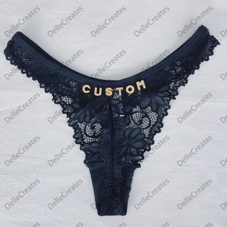 May include: Black lace underwear with the word "CUSTOM" written in gold rhinestones.