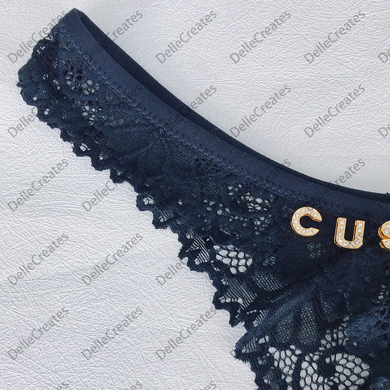 May include: Black lace underwear with a gold "CUS" embellishment.