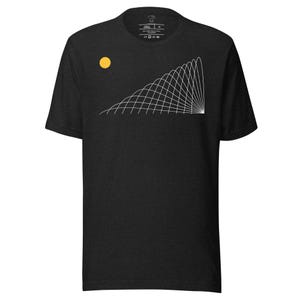 Puede incluir: Camiseta gris oscuro con un círculo amarillo y un diseño geométrico blanco. El diseño consiste en una serie de líneas curvas que se extienden desde un punto central. La camiseta tiene cuello redondo y mangas cortas.