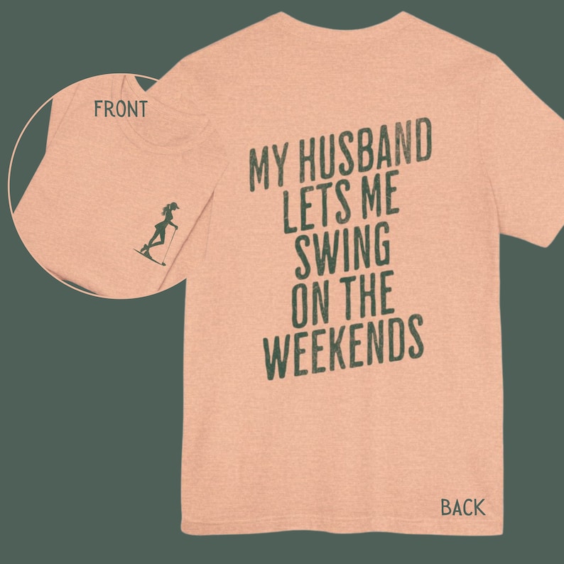 Może przedstawiać: R&oacute;żowy t-shirt z nadrukiem "My husband lets me swing on the weekends" na plecach w ciemnozielonym kolorze.