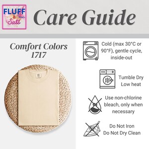 May include: A beige Comfort Colors 1717 t-shirt is displayed on a woven mat. The image includes a care guide with instructions for washing, drying, and bleaching. The guide recommends cold water, low heat, and no ironing or dry cleaning.