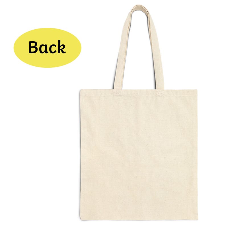 Puede incluir: Un bolso tote de color crema con asas largas. La bolsa est&aacute; hecha de una tela lisa y sin adornos. Un &oacute;valo amarillo con la palabra "Back" en texto negro est&aacute; en la esquina superior izquierda. La bolsa est&aacute; vac&iacute;a y lista para usar.