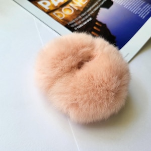 May include: A fluffy, light pink hair scrunchie.