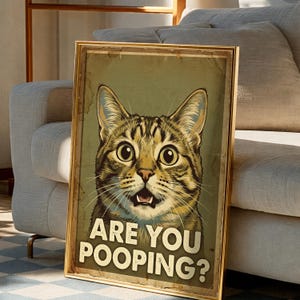 Könnte beinhalten: Gerahmtes Poster mit einer Illustration einer überraschten Tabby-Katze. Der Text "ARE YOU POOPING?" ist in Weiß gehalten. Das Poster hat ein Vintage-Aussehen. Der Rahmen ist goldfarben.