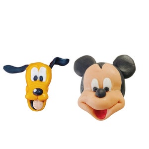 May include: Two cartoon character face decorations. One is Pluto, a yellow dog with black ears and a tongue sticking out. The other is Mickey Mouse, with black ears, a tan face, and a red tongue.
