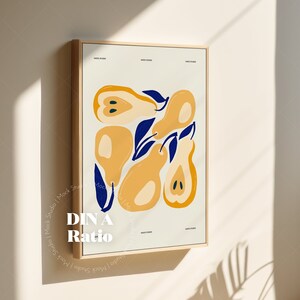 May include: A framed print with a minimalist design featuring yellow pears with blue leaves on a white background. The frame is light wood and the print is titled "DIN A Ratio".