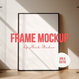 May include: A black frame mockup with a white background. The frame is on a light brown wooden floor. The text "FRAME MOCKUP by Mock Studio" is in red letters below the frame. A white circle with the text "DIN A RATIO" in red letters is on the right side of the frame.